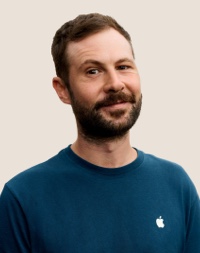 Portrait of a smiling Apple Retail team member with dark hair and a beard.