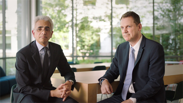 兩個穿著西裝的人坐在桌前。