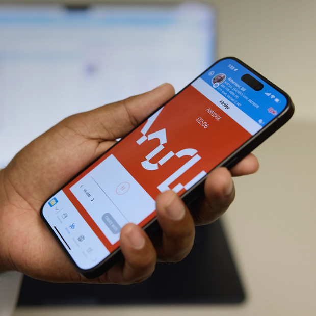 يد تحمل جهاز iPhone تعرض تطبيق Abridge الذي يترجم المحادثات بين المريض والطبيب إلى ملاحظات سريرية.