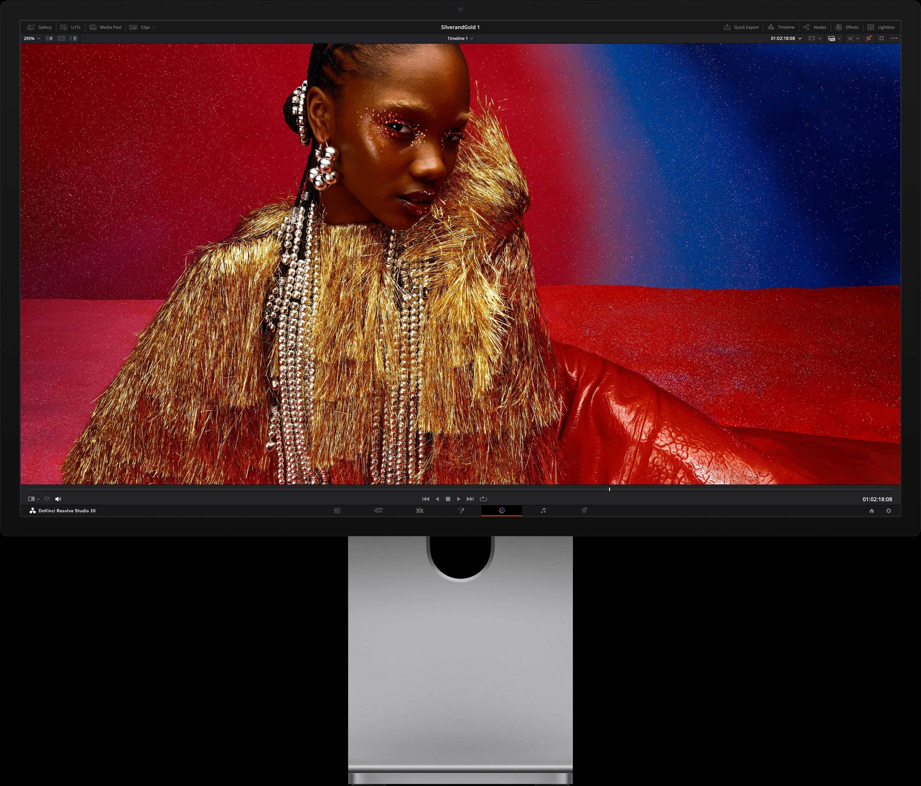 سيدة ترتدي فستاناً أحمر زاهياً واكسسوارات معدنية كبيرة الحجم تجلس أمام خلفية يتدرج لونها بالأزرق والأحمر، لتوضيح جودة الصورة التي تقدمها شاشة Studio&nbsp;Display&nbsp;XDR